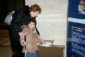 Brianna, 8 years old, reads the Braille transcription while her mother, Margaret Cameron, observes.